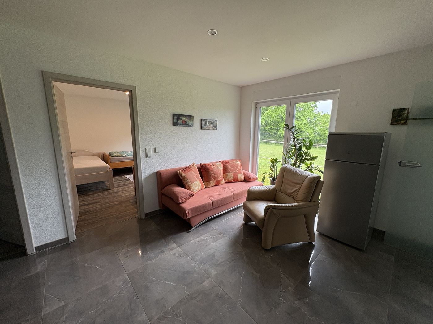 Wohnbereich von Wohnung 1 mit Schlafcouch, Sessel und Terrassentür