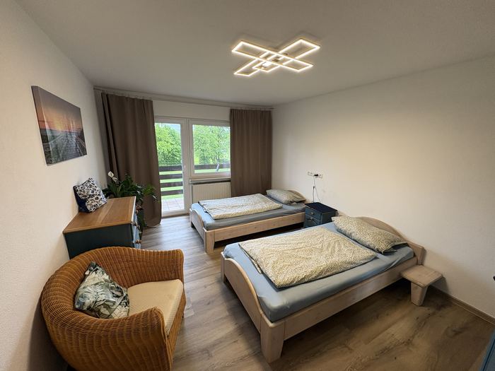 Helles Schlafzimmer mit zwei Betten und Balkontür in Wohnung 2